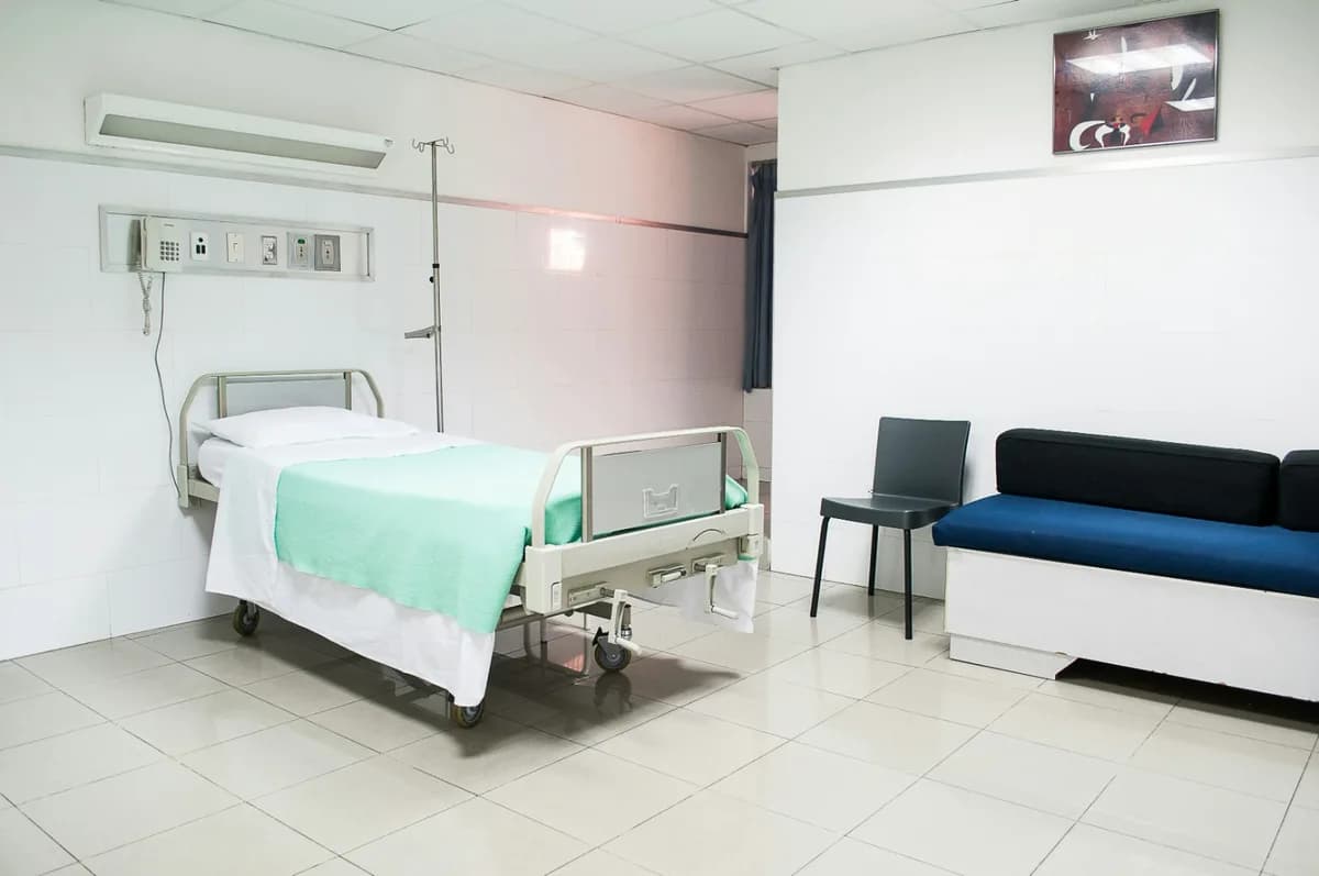 Chambre d’hôpital avec lit médicalisé, sol et murs carrelés lessivables