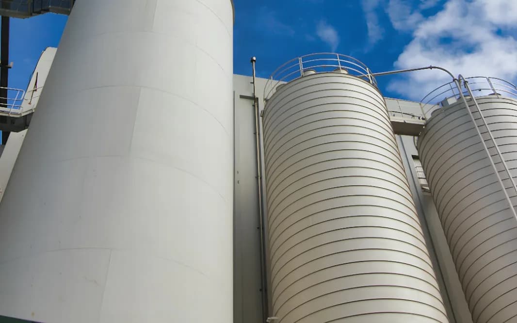 Silos d’un site industriel vus en contre-plongée, passerelles et garde-corps métalliques